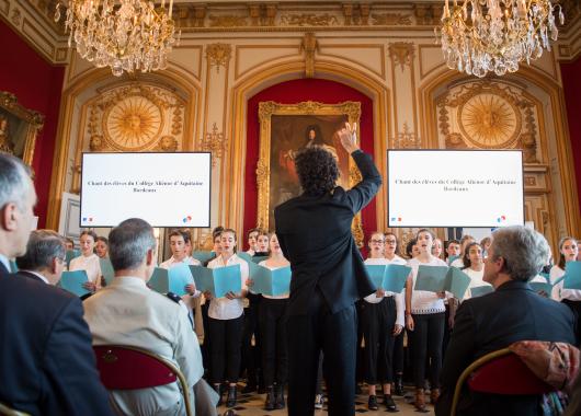 Des collégiens chantant devant un corps d'armée