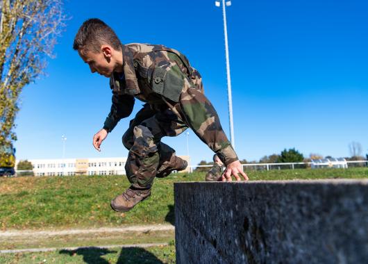 Un élève franchit un mur obstacle