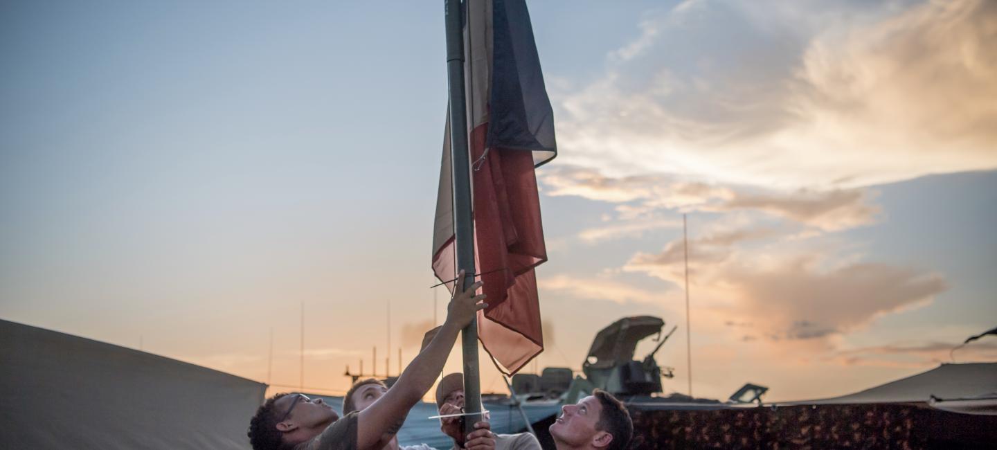 4 soldats hissant le drapeau Français dans un QG en OPEX